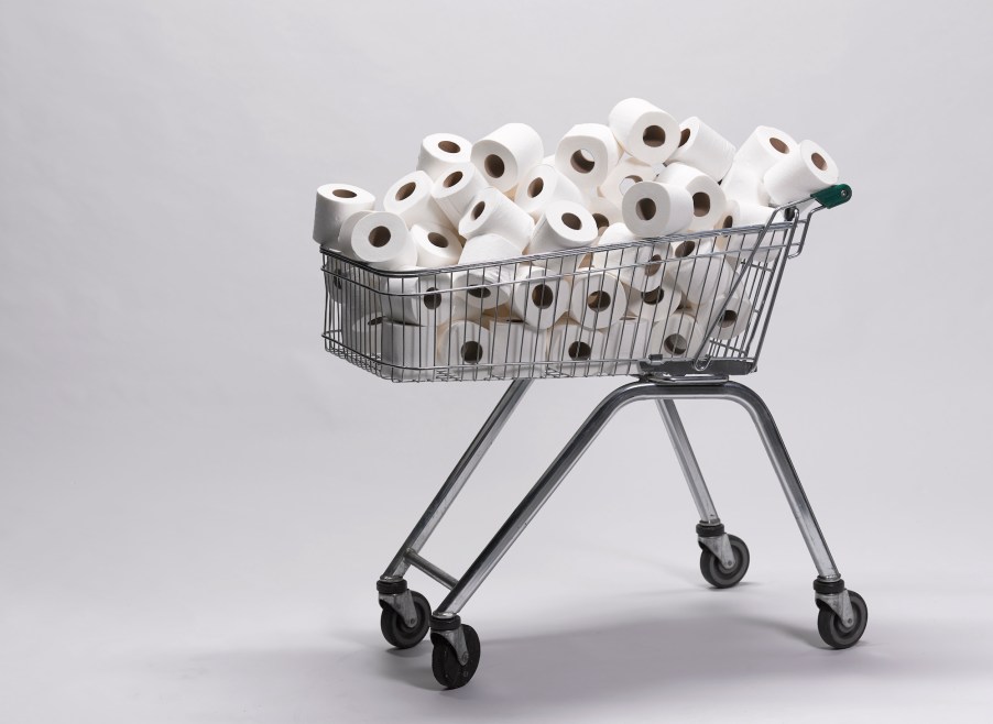 Photo illustration of a pile of unwrapped white toilet paper rolls in a metal shopping cart