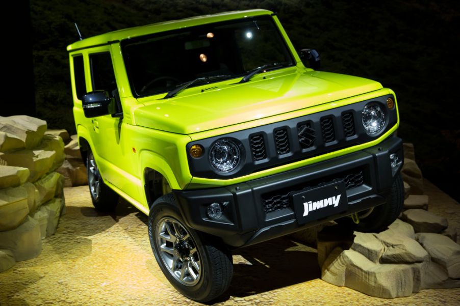 A neon green Suzuki Jimny on display with stage rocks