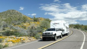 A truck tows a camper down an open road