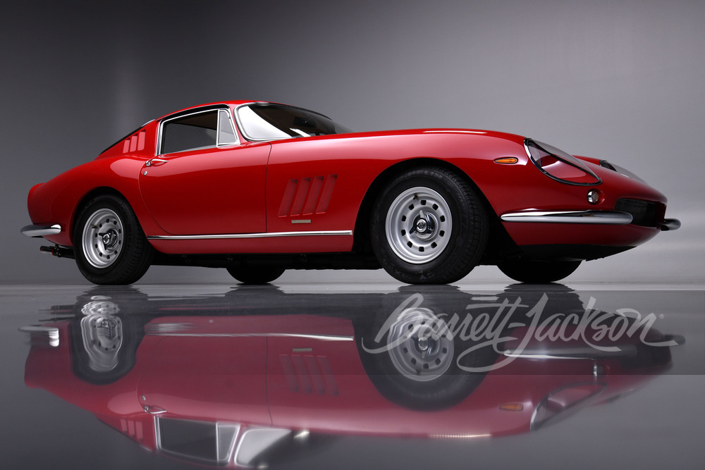 A red 1965 Ferrari 275 GTB/4 on a display with a clear reflection beneath it