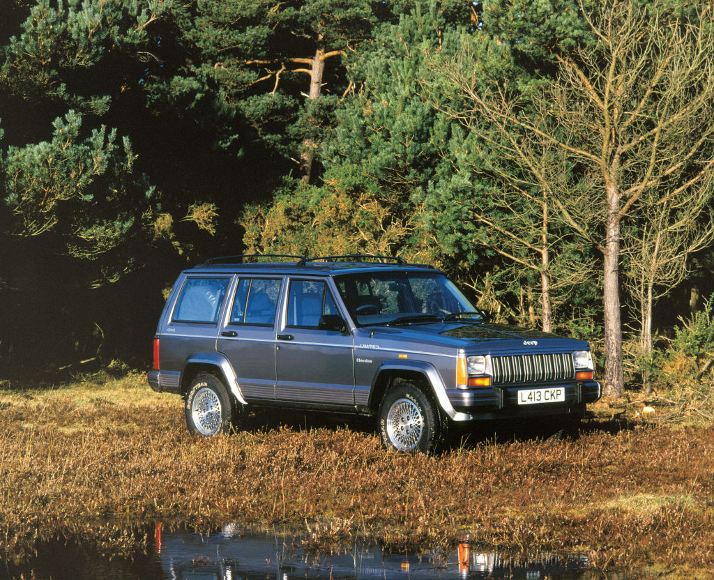 A blue Jeep Grand Cherokee SUV parked in the forest