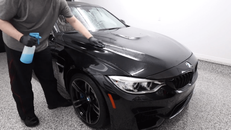 A detailer clay bars a BMW in a garage