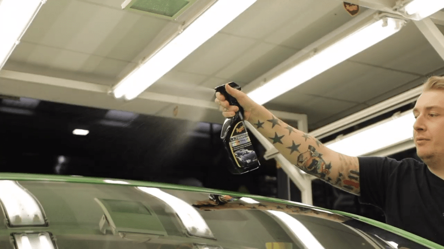 A detailer sprays Meguair's Quick Detailer onto a car