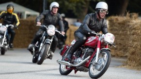 A black-clad rider on a red-and-silver 1967 Ducati Mach 1 leads 1966 BMW R50 and 1969 Norton Commando at a 2004 Hamburg, Germany race