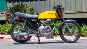 The side view of a yellow 1976 Honda CB400F Super Sport in a parking lot