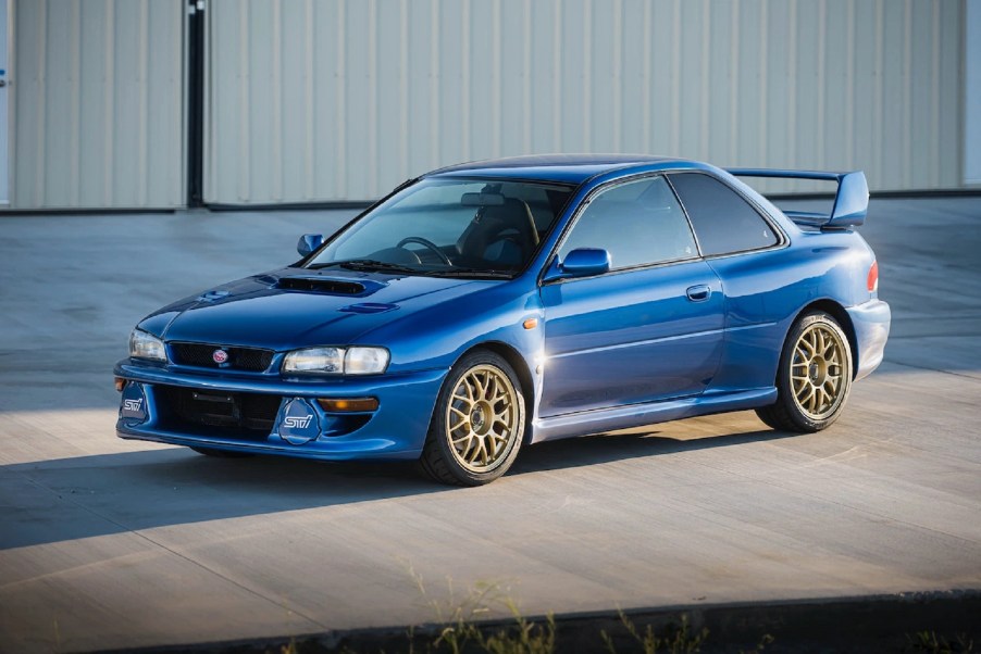 A blue 1998 Subaru Impreza 22B STi parked by a warehouse