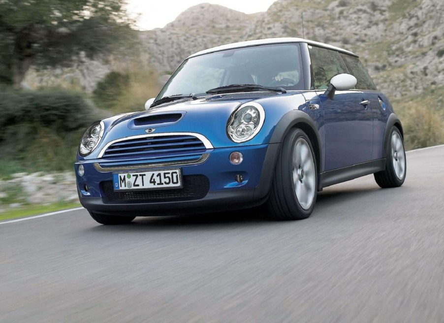 A blue 2006 'R53' Mini Cooper S drives down a valley road