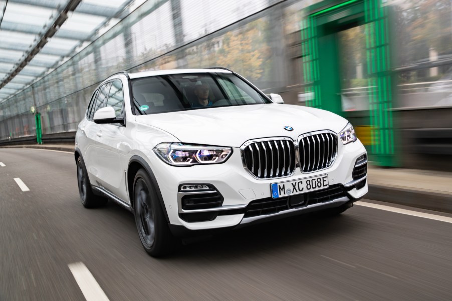 A white 2021 BMW X5 midsize crossover luxury SUV travels on a covered road