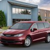 A dark-red 2021 Chrysler Voyager parked outside a modern two-story building