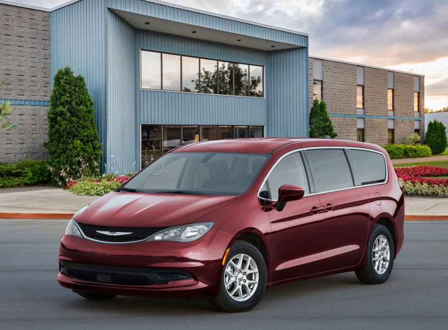 A dark-red 2021 Chrysler Voyager parked outside a modern two-story building