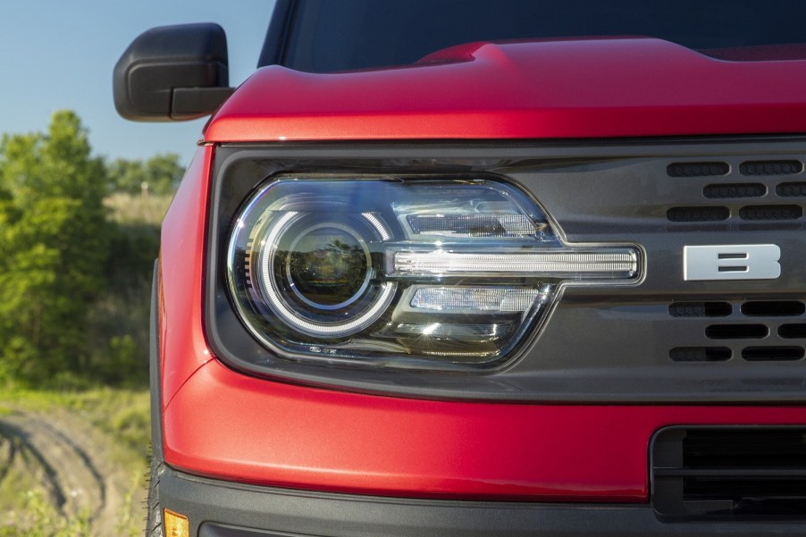 The right front headlight and black grille of a red 2021 Ford Bronco Sport SUV