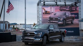 A black Ford F-150 underneath an American flag