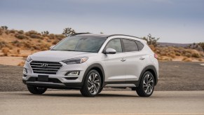 A shite 2021 Hyundai Tucson compact SUV parked on a two-lane road in a desert