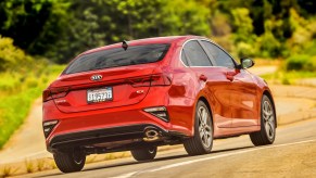 A red 2021 Kia Forte compact car traveling on a rural road