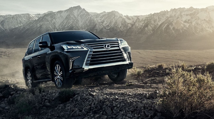 A black 2021 Lexus LX 570 climbs up a hill in the desert by some mountains