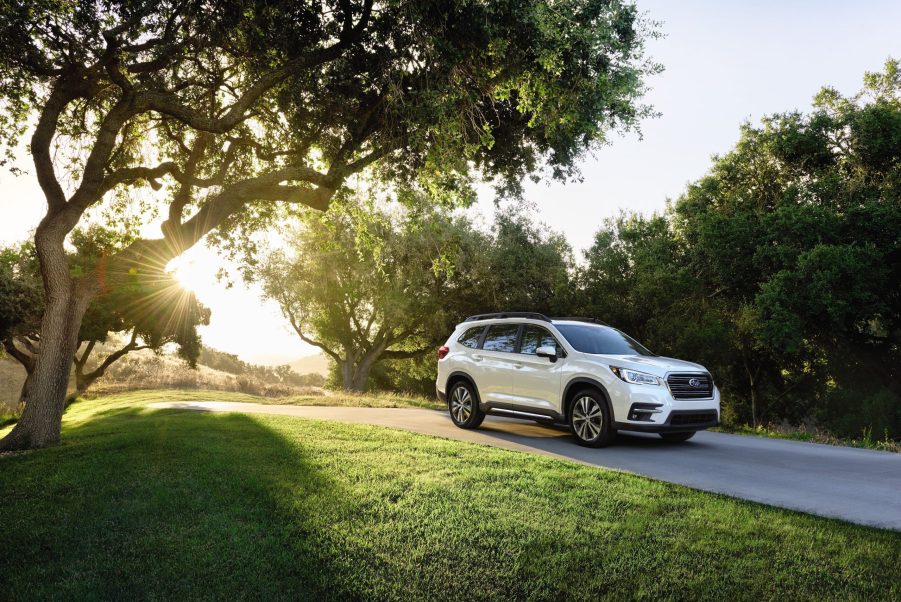 a white 2021 subaru ascent, trim level base, driving down a tree-lined road