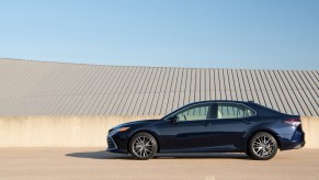 A navy-blue 2021 Toyota Camry XLE midsize sedan parked on a beige concrete roof with a blue sky in the background