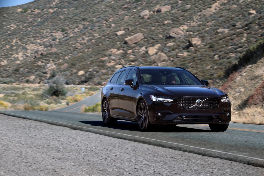 A black 2021 Volvo V90 station wagon on a two-lane mountain highway