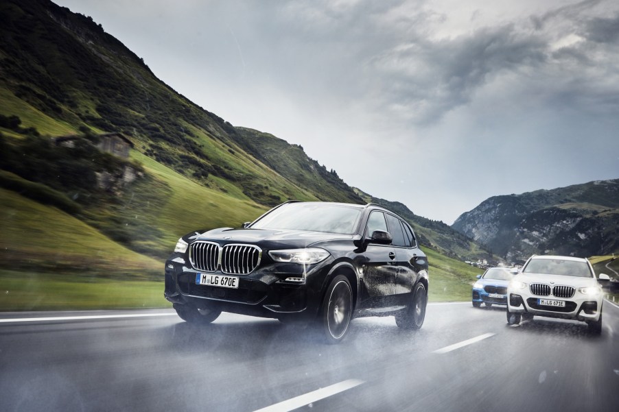 Three BMWs driving down a wet mountain road