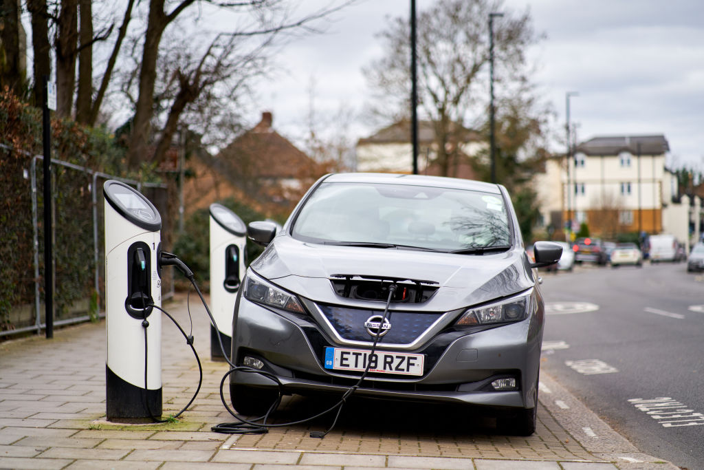 A gray nissan leaf parked at a charging station