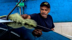 Pictured is a man cleaning his car, which can help increase the resale value.