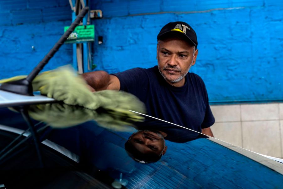 Pictured is a man cleaning his car, which can help increase the resale value.