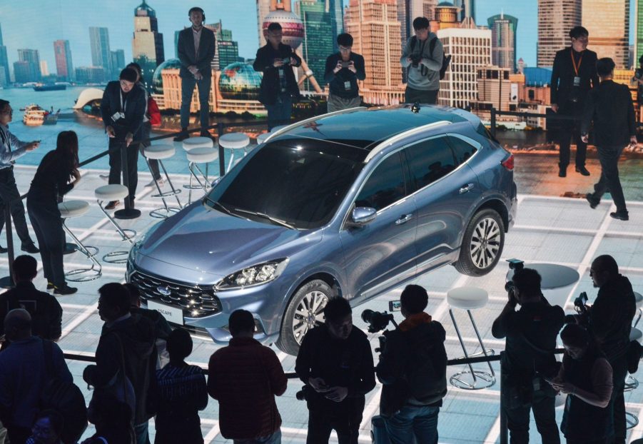 Photographers taking photos of a new blue Ford Escape car during a press conference in Shanghai ahead of the Shanghai Auto Show