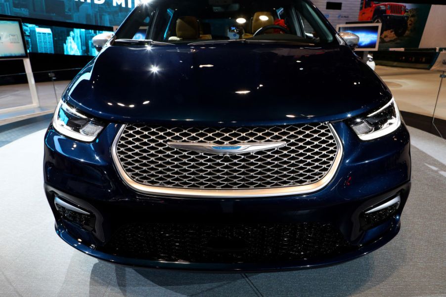 the grille of a dark blue 2021 Chrysler Pacifica minivan on display at an auto show