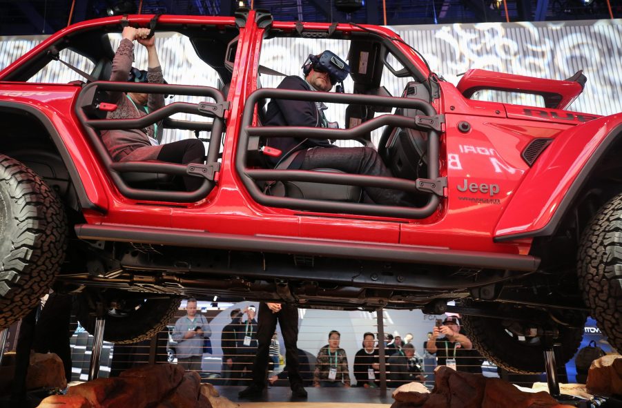 An attendee wears a virtual reality headset while riding in a show version of a red 2020 Jeep Wrangler Unlimited 4xe plug-in hybrid electric vehicle at CES 2020