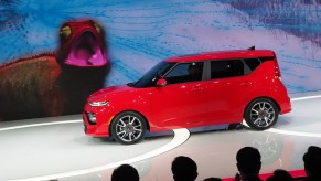 A red Kia Soul GT being unveiled at an auto show.