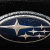 The Subaru Logo with flecks of water on it.