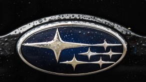 The Subaru Logo with flecks of water on it.