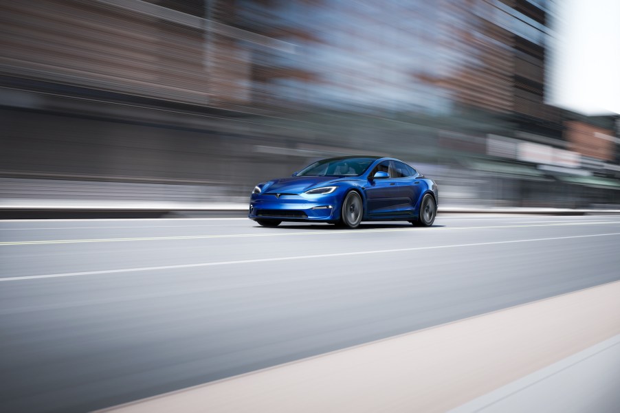 A blue Tesla Model S travels on a multilane city highway