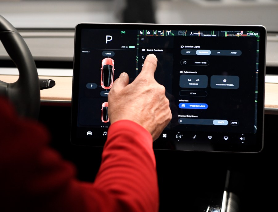 A man's finger touches a Tesla Model 3's 15-inch control touchscreen in May 2018