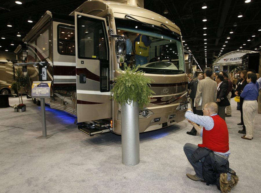 A woman takes a picture of an RV at a trade show