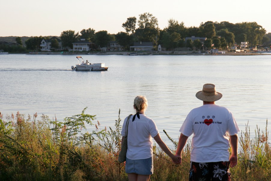 A couple holds hands while looking at a pontoon boat on Pine Lake in La Porte, Indiana