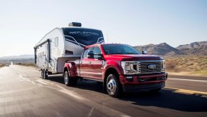 A red 2021 Ford F-350 Super Duty hauling a camper in a rural area