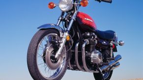 A low-angle front 3/4 view of an orange-and-brown 1973 Kawasaki Z1 900 on a desert road