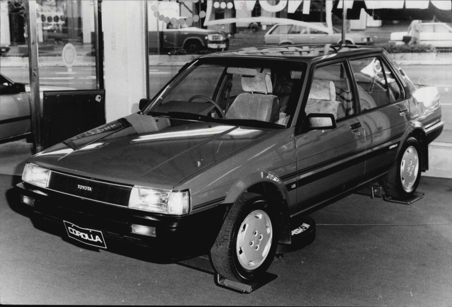 A black-and-white-photo of a Toyota Corolla compact sedan in a showroom on June 11, 1985