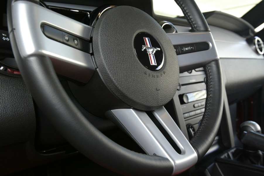 A black and silver three-spoke steering wheel inside a 2005 Ford Mustang GT