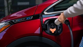 A person charges a red 2020 Chevrolet Bolt EV