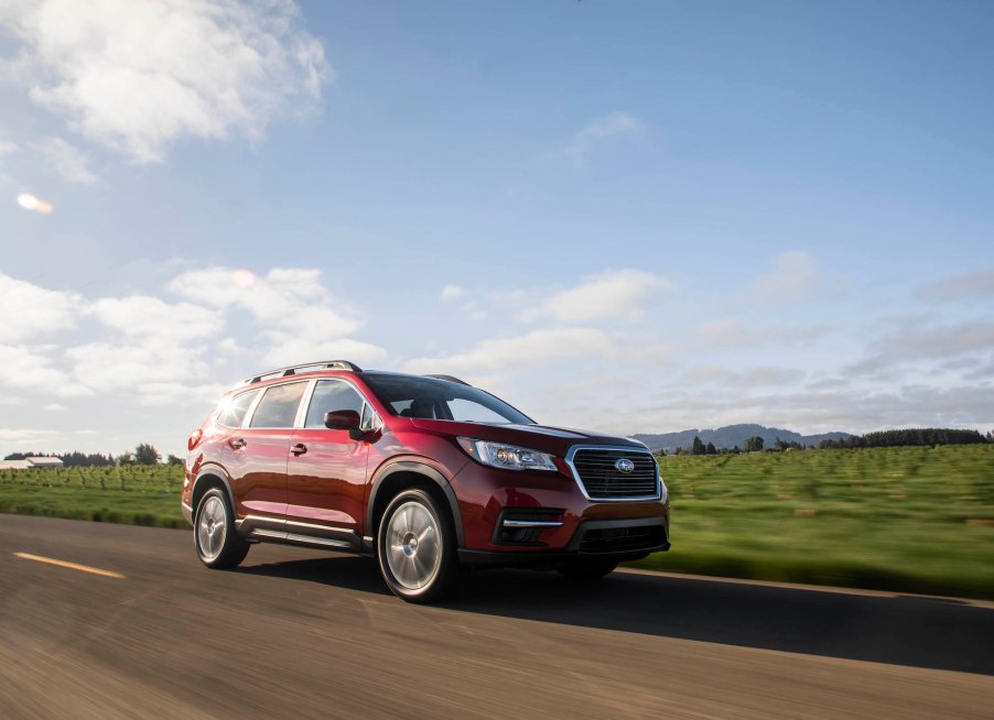 A red 2020 Subaru Ascent midsize SUV traveling on a rural road on a sunny day