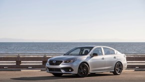 A silver 2020 Subaru Legacy Sport parked in front of a large body of water with mountains behind it