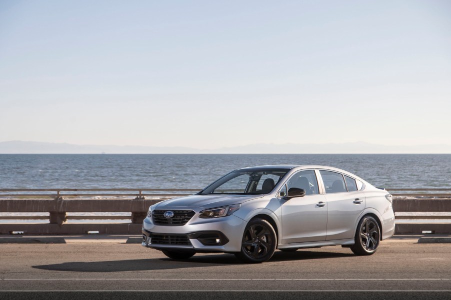 A silver 2020 Subaru Legacy Sport parked in front of a large body of water with mountains behind it