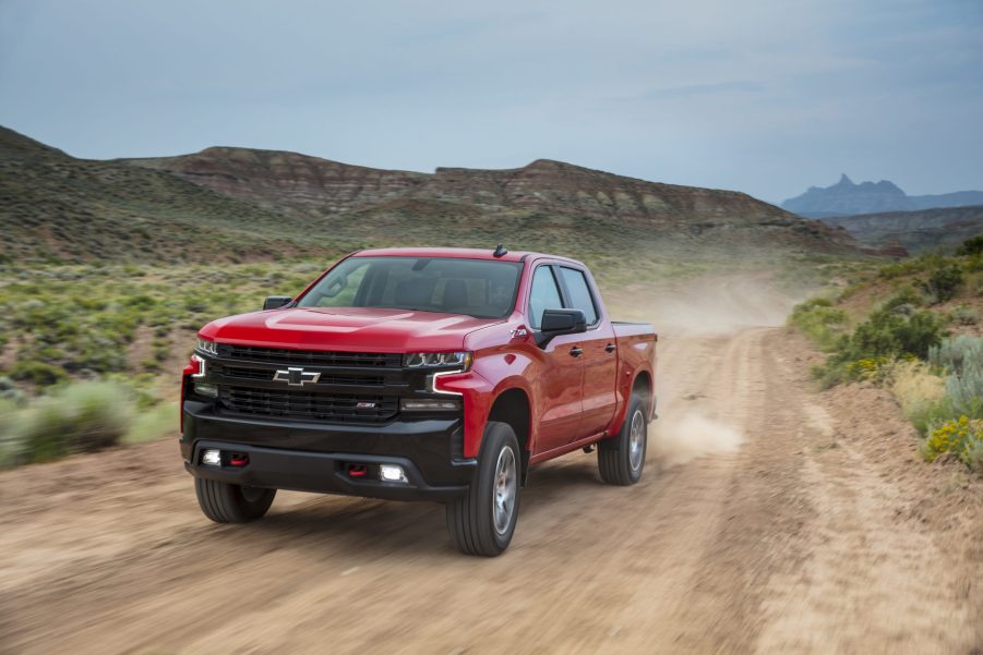 A red 2021 Chevy Silverado pickup truck driving on a dirt road