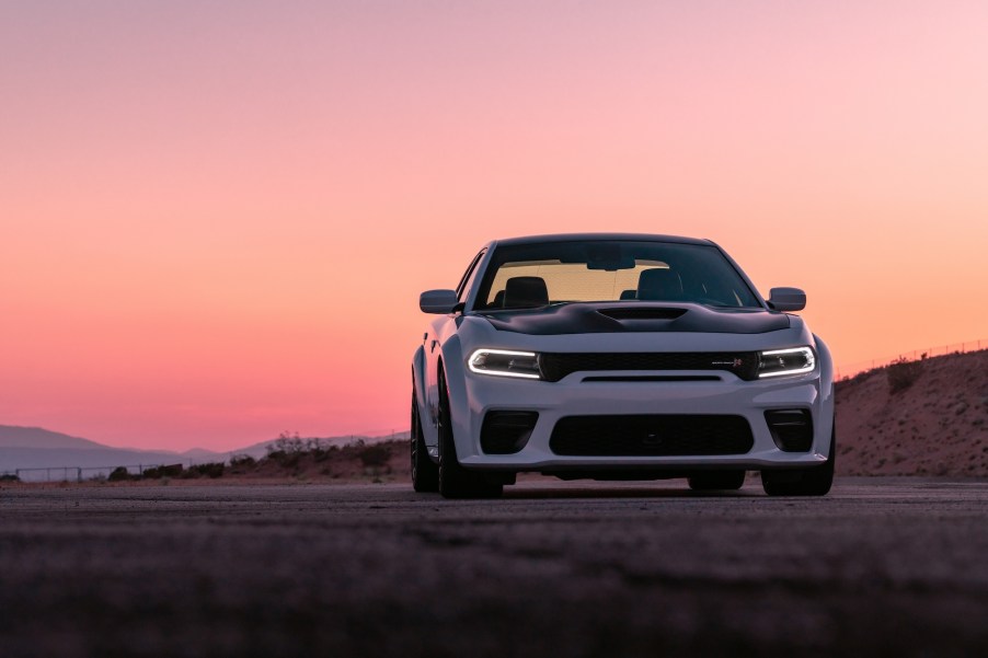 A white and black 2021 Dodge Charger parked in front of mountains at sunset