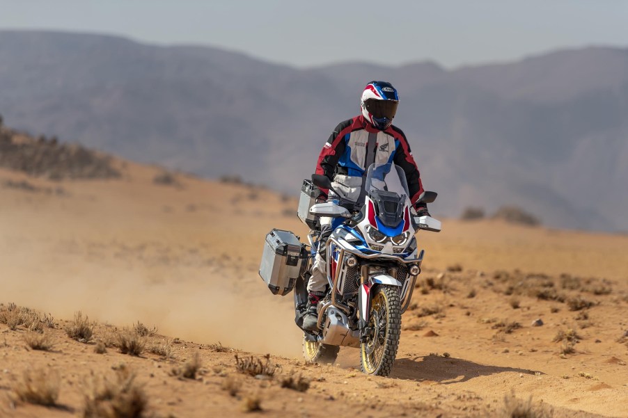 A white-red-and-blue-clad rider takes a white-red-and-blue 2021 Honda Africa Twin DCT through the desert