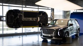 A black 2021 Hyundai Palisade on display next to another Palisade hung to display its underside