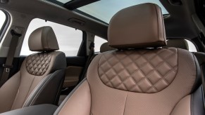 An interior photo of the tan leather front seats and panoramic sunroof of a 2021 Hyundai Santa Fe midsize SUV