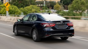 A navy blue 2021 Toyota Camry midsize sedan traveling on a city highway